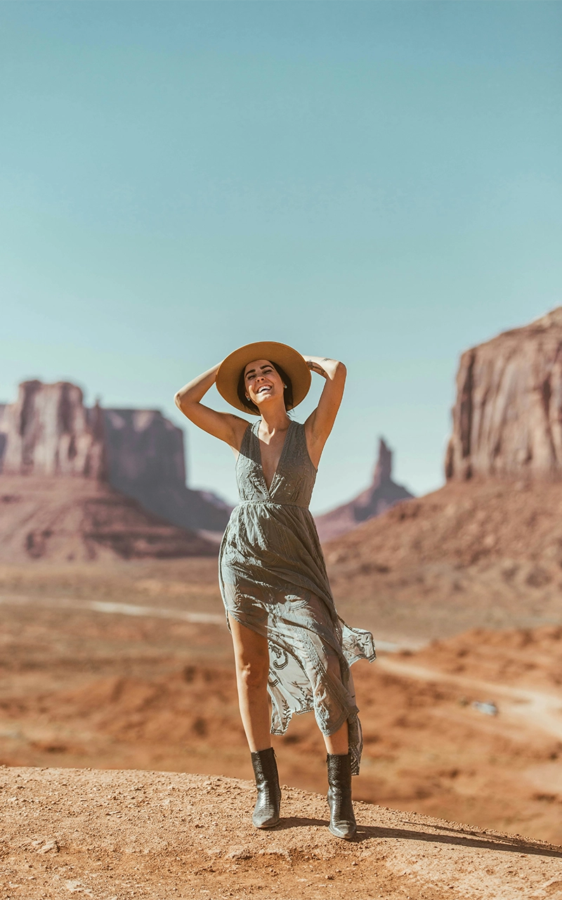 happy young woman standing in front of monument valley smiling photo by taylor brandon